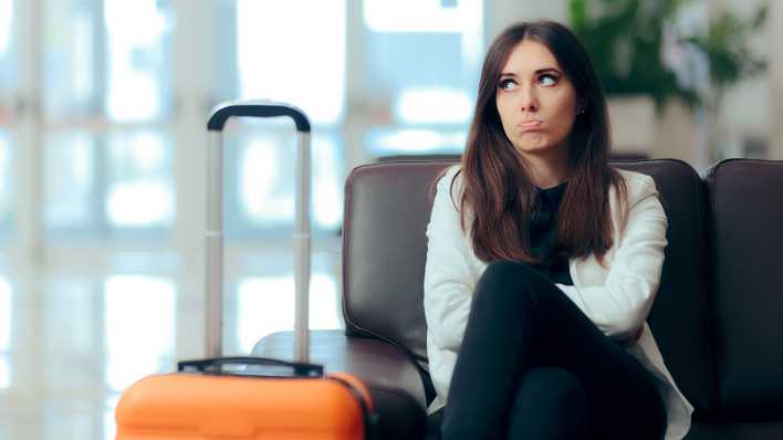 Frau sitzt mit Koffer am Flughafen, Foto: Colourbox.com